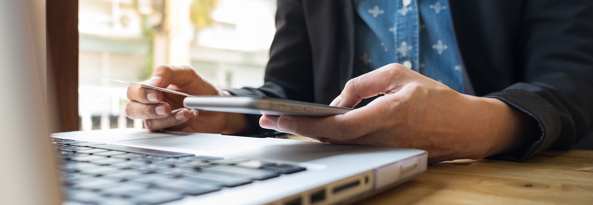 person on laptop holding debit card and cell phone